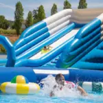 Criança num insuflável aquático do Arcadalândia, parque aquático gratuito em Braga, no Nova Arcada. Baseado no comunicado enviado, que refere o funcionamento até 31 de agosto, o horário das 14h00 às 21h00, entrada gratuita, capacidade de 60 participantes por sessão e mais de 11 mil visitas registadas.