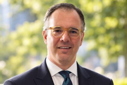 Retrato do deputado Carlos Barbosa, de fato escuro e óculos, ao ar livre