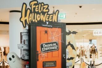 Porta cor de laranja com o letreiro “Doçura ou travessura?”, abóboras e um fantasma decorativo num centro comercial