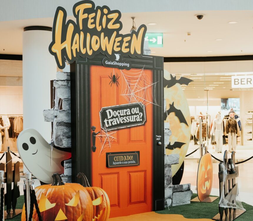 Porta cor de laranja com o letreiro “Doçura ou travessura?”, abóboras e um fantasma decorativo num centro comercial